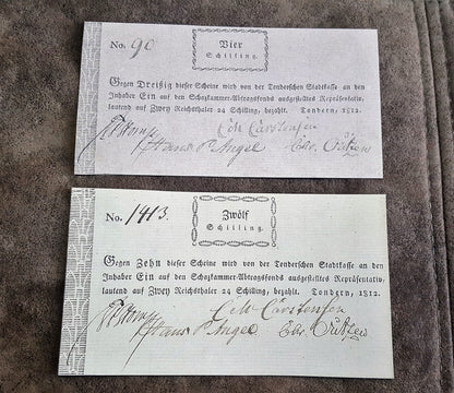 Historical German States early 19th-century paper money notes issued in Sundern, dated 1812, featuring denominations of 4 Schilling ("Vier Schilling") and 12 Schilling ("Zwölf Schilling") with handwritten serial numbers and official signatures.